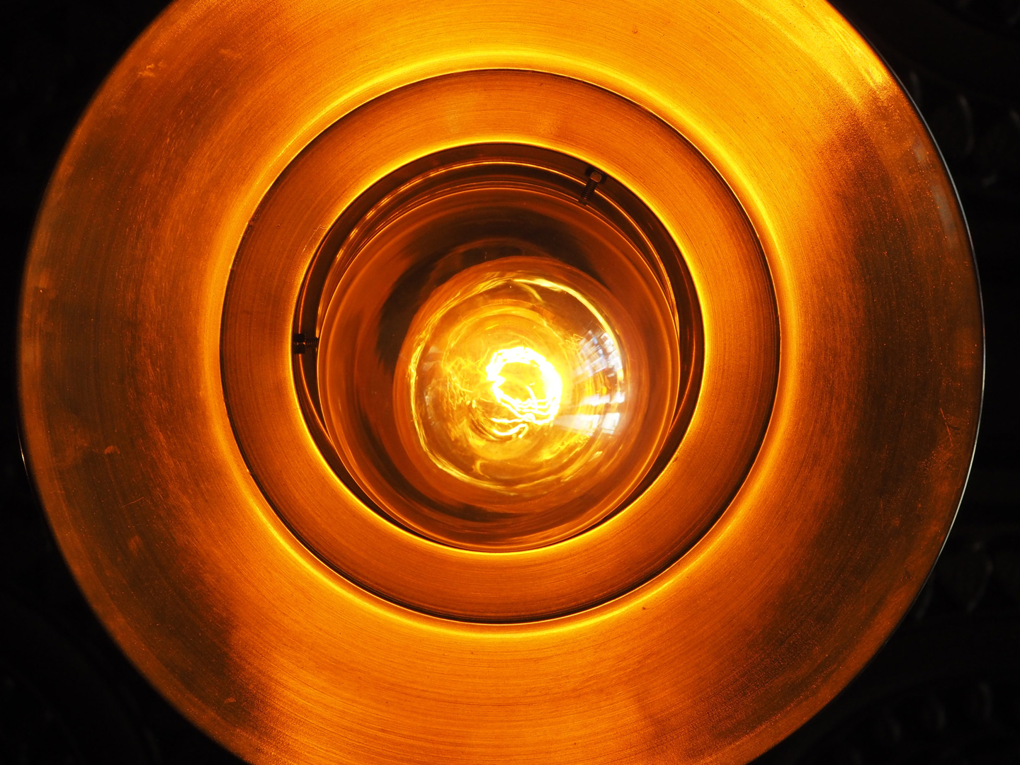 Close-up view of a glowing filament inside a round vintage light bulb.