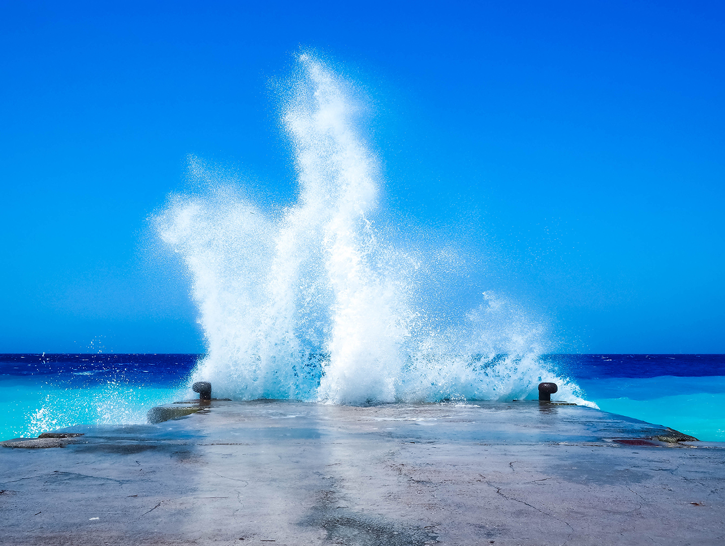 View of waves crashing into a concrete pier on the island of Rhodos.